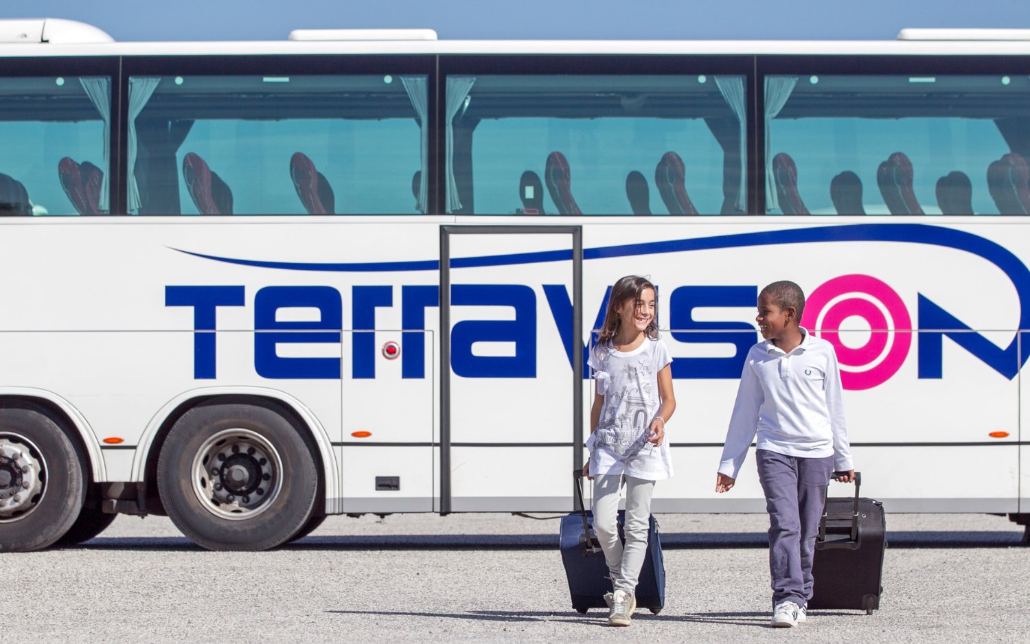 Kids with luggage walking by Terravision bus at Istanbul airport transfer.