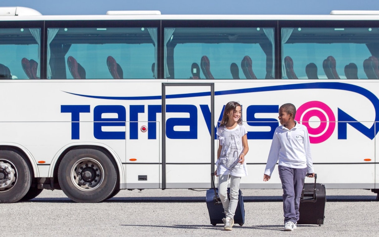 Kids with luggage walking by Terravision bus at Istanbul airport transfer.