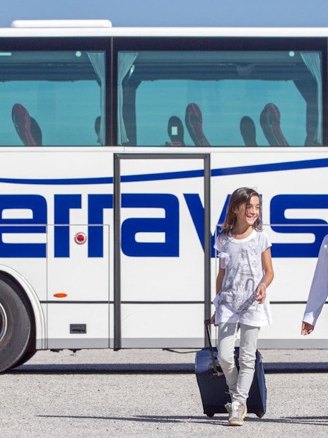 Kids with luggage walking by Terravision bus at Istanbul airport transfer.
