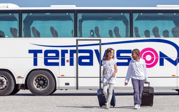 Kids with luggage walking by Terravision bus at Istanbul airport transfer.