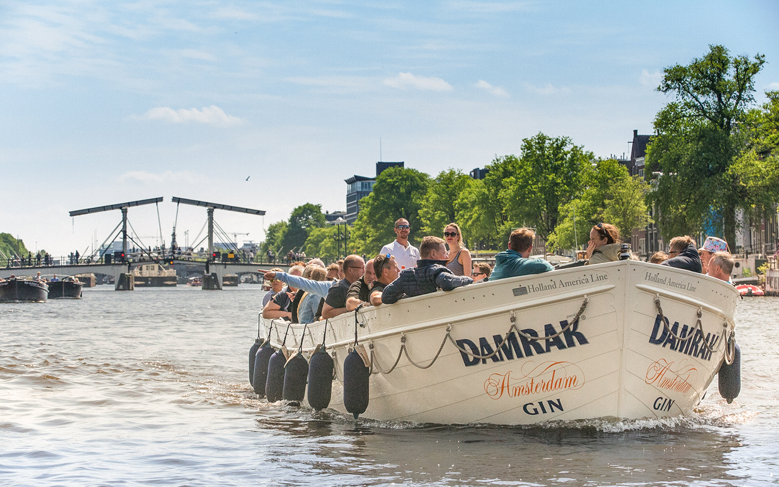 Luxury cruise boat on Amsterdam canal with Magere Brug in background, Netherlands.
