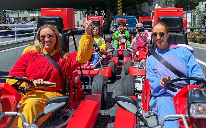 Group enjoying go-karting in colorful costumes on Shibuya streets, Tokyo.