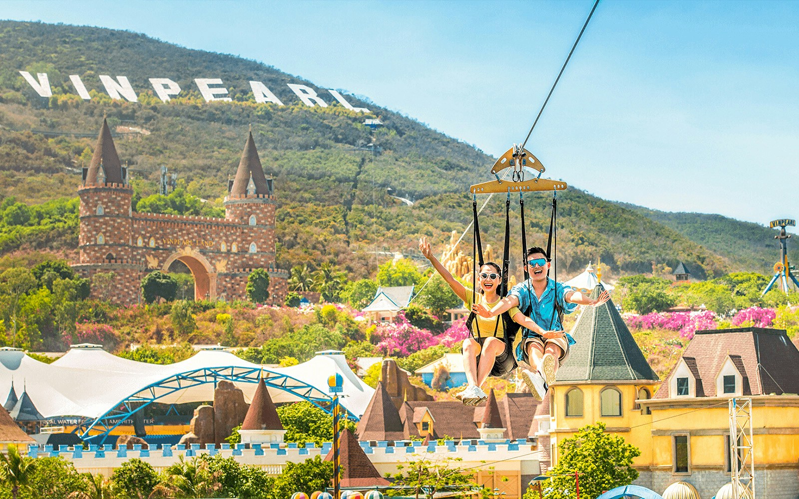 Couple enjoying a ride at VinWonders Nha Trang Theme Park with Vinpearl sign in background.