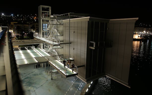 Centro Botín in Santander at night with illuminated walkways and water reflections.
