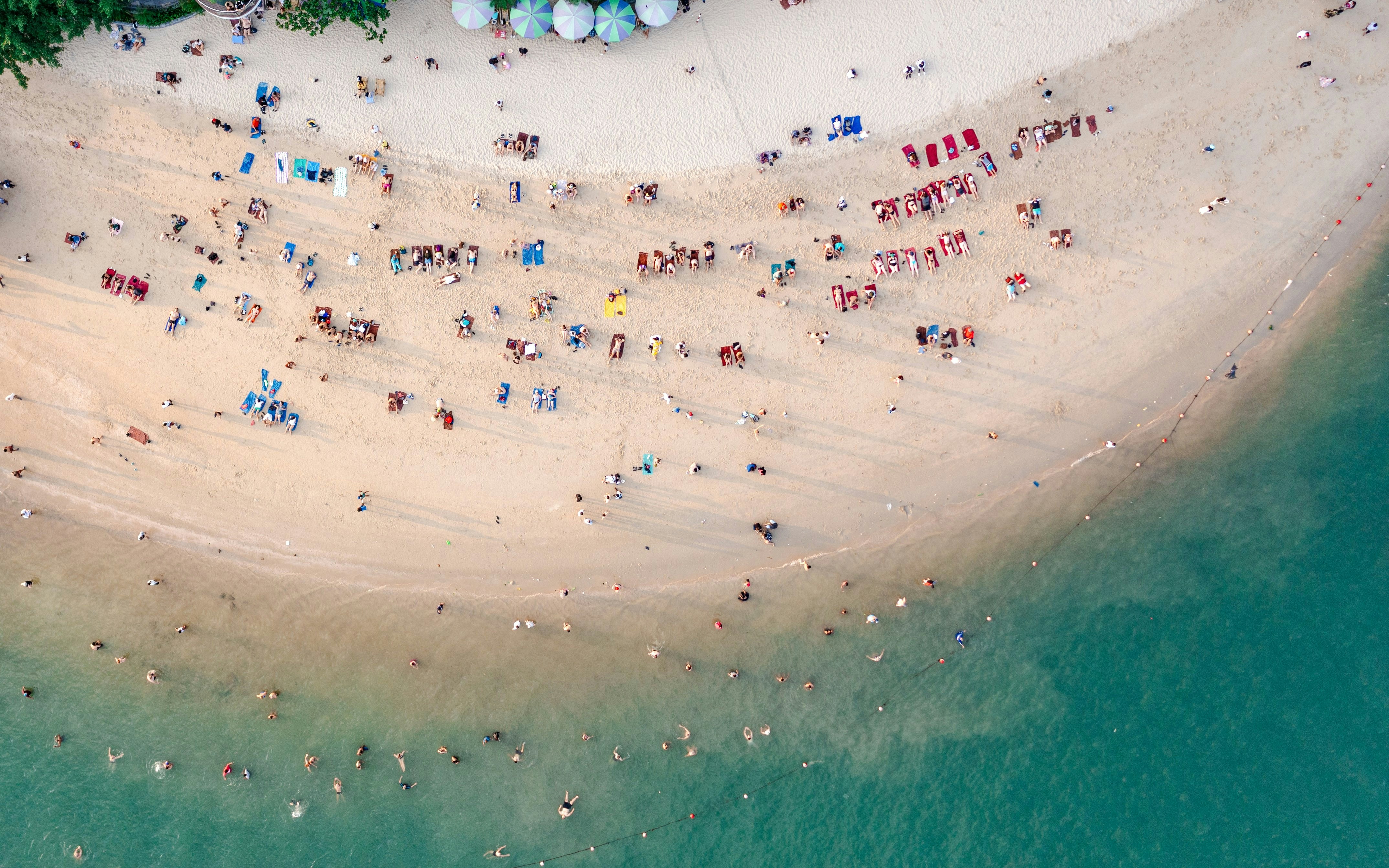 Aerial view of a crowded beach with sunbathers and swimmers in Ha Long Bay, Vietnam.