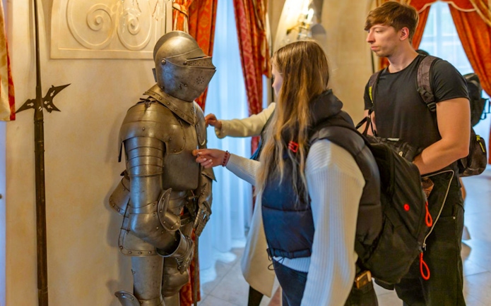Visitors examining medieval armor at Dětenice Castle during Prague tour.