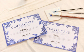 Certificates from Dutch blue tile painting workshop with brushes and painted tile.