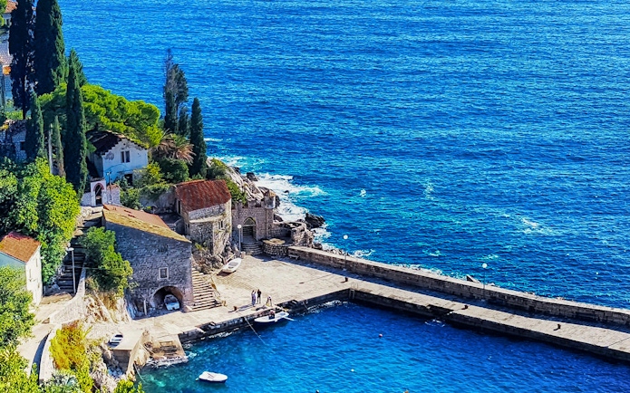 Coastal view of a stone pier and buildings in Dubrovnik, Croatia, featured in Game of Thrones.