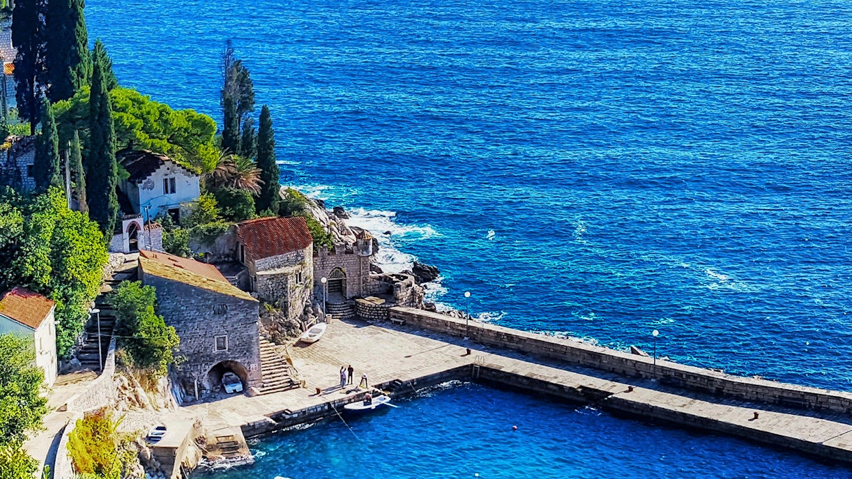 Coastal view of a stone pier and buildings in Dubrovnik, Croatia, featured in Game of Thrones.