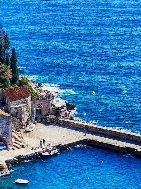 Coastal view of a stone pier and buildings in Dubrovnik, Croatia, featured in Game of Thrones.