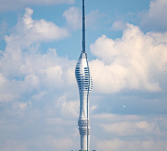 Camlica Tower in Istanbul rising above a green landscape under a cloudy sky.