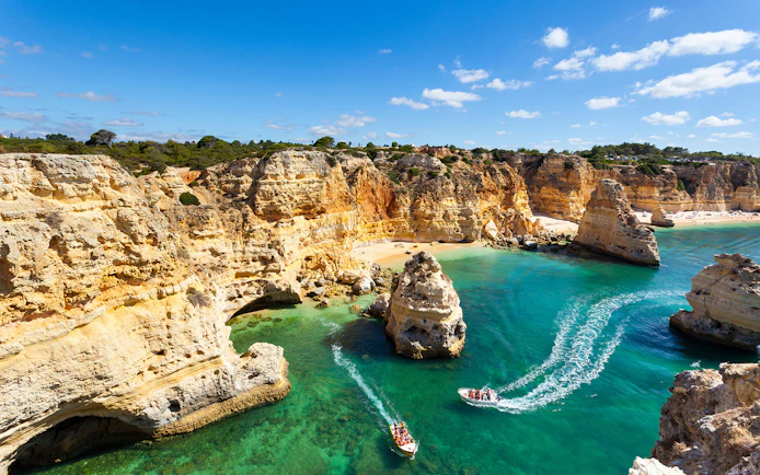 Boats touring the Benagil Caves along the Albufeira coastline, Portugal.