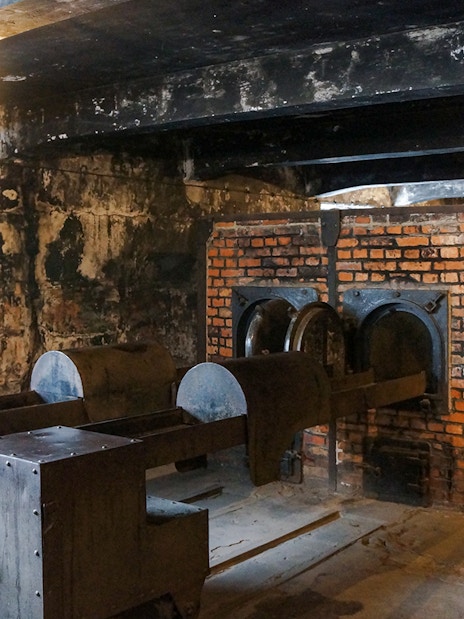 Auschwitz I crematorium interior with brick ovens and metal structures.