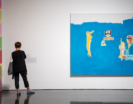 Visitor viewing contemporary art at Museu d'Art Contemporani de Barcelona, featuring vibrant paintings.