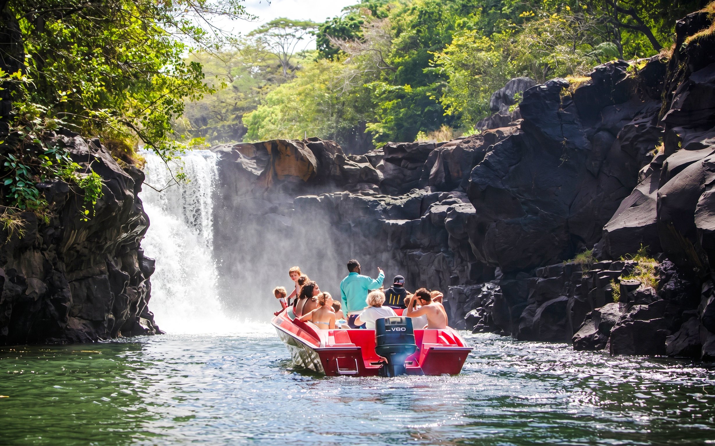 Tourists on a boat approaching a waterfall near Ile aux Cerf, Mauritius.