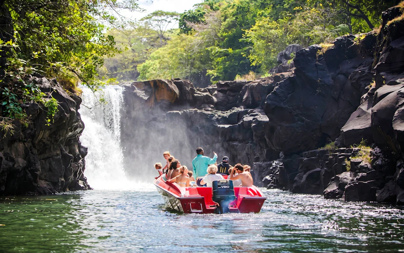 Tourists on a boat approaching a waterfall near Ile aux Cerf, Mauritius.