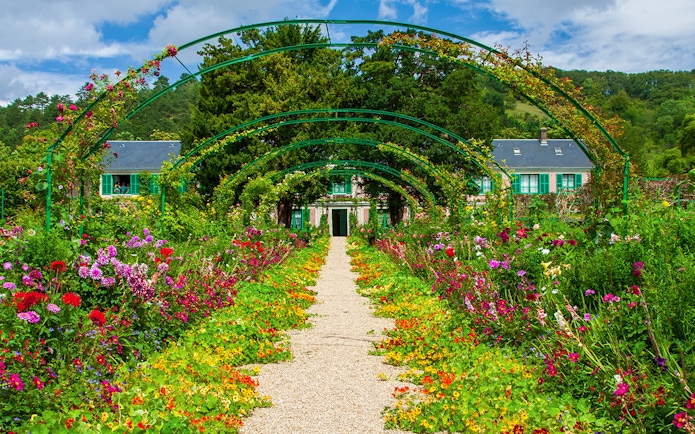 Pathway through vibrant gardens leading to Monet's House in Giverny, France.