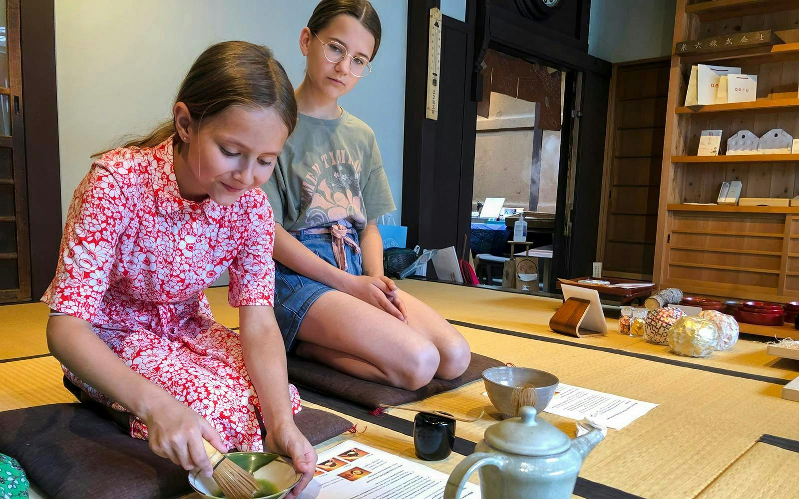 Young kids participating in a tea ceremony, making matcha with a tea master.