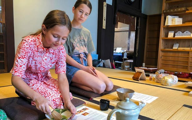 Young kids participating in a tea ceremony, making matcha with a tea master.