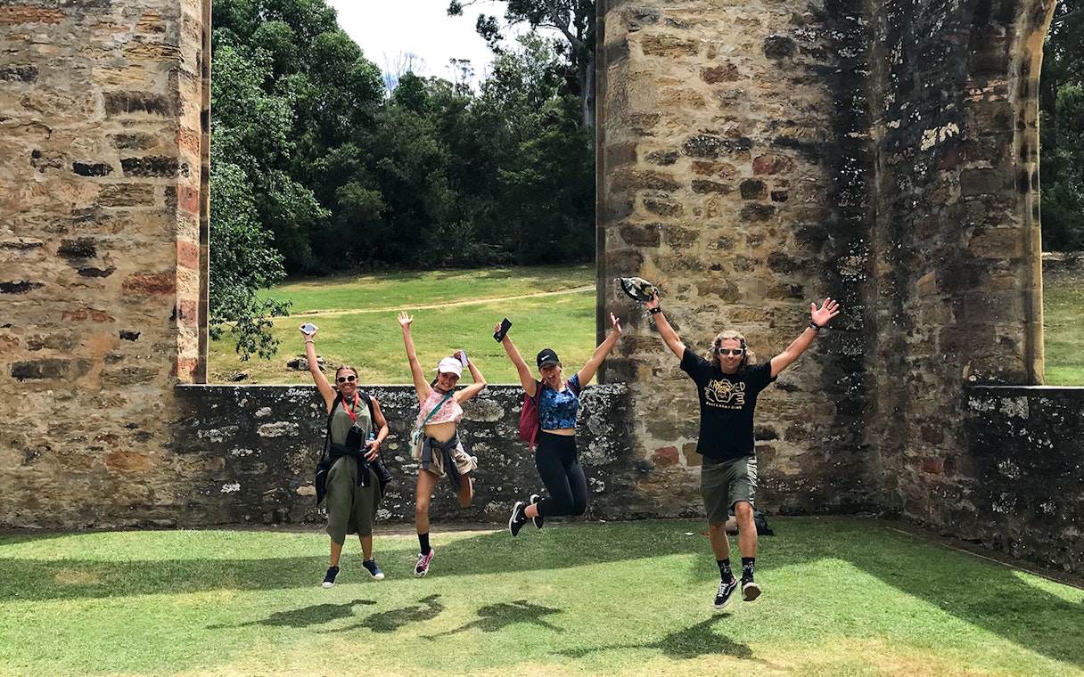 Visitors jumping in front of historic ruins at Port Arthur, Tasman Peninsula.