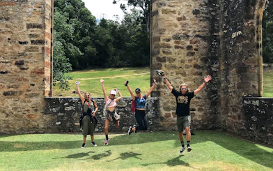 Visitors jumping in front of historic ruins at Port Arthur, Tasman Peninsula.