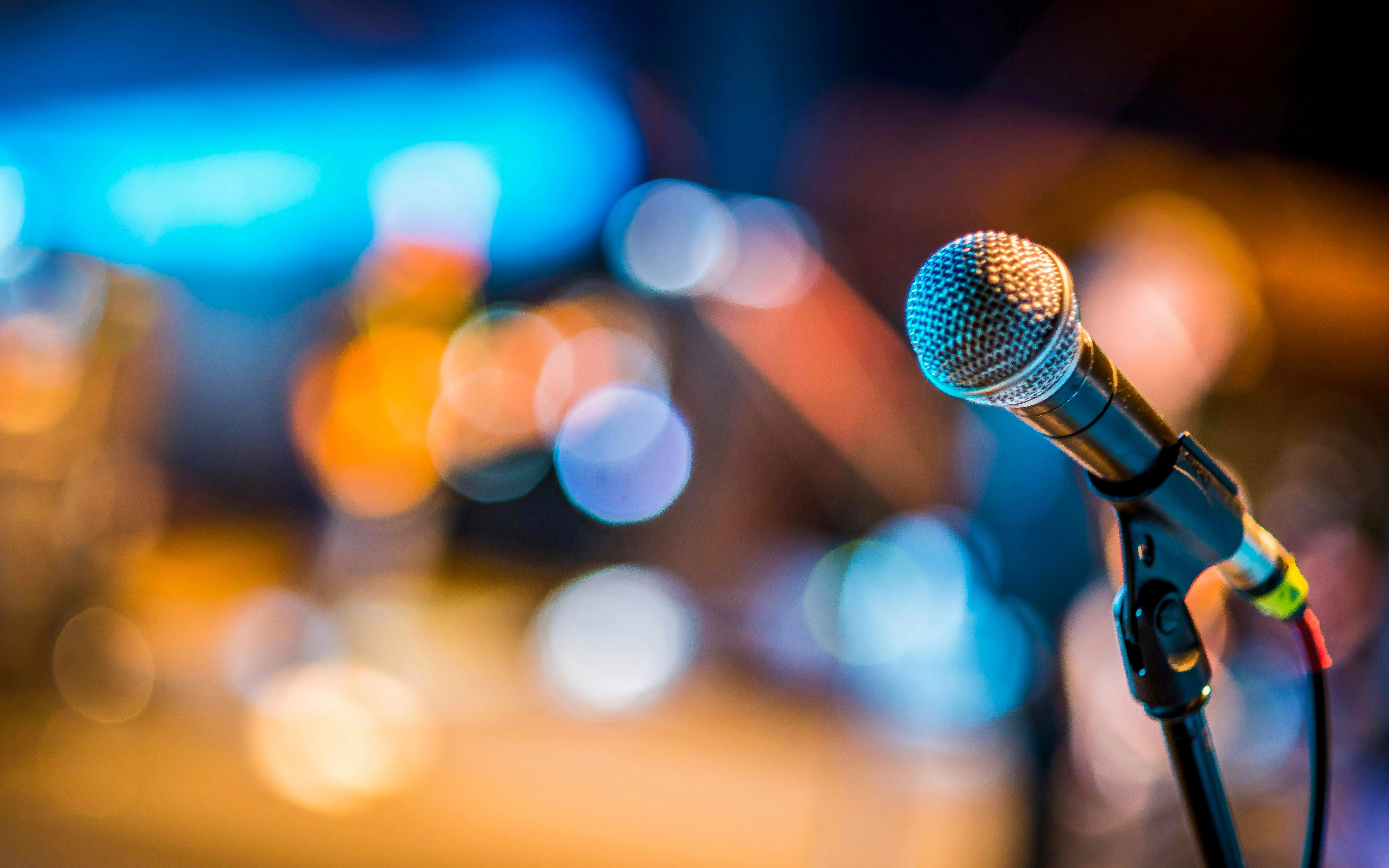 Classic microphone on stage with colorful concert lights in background.