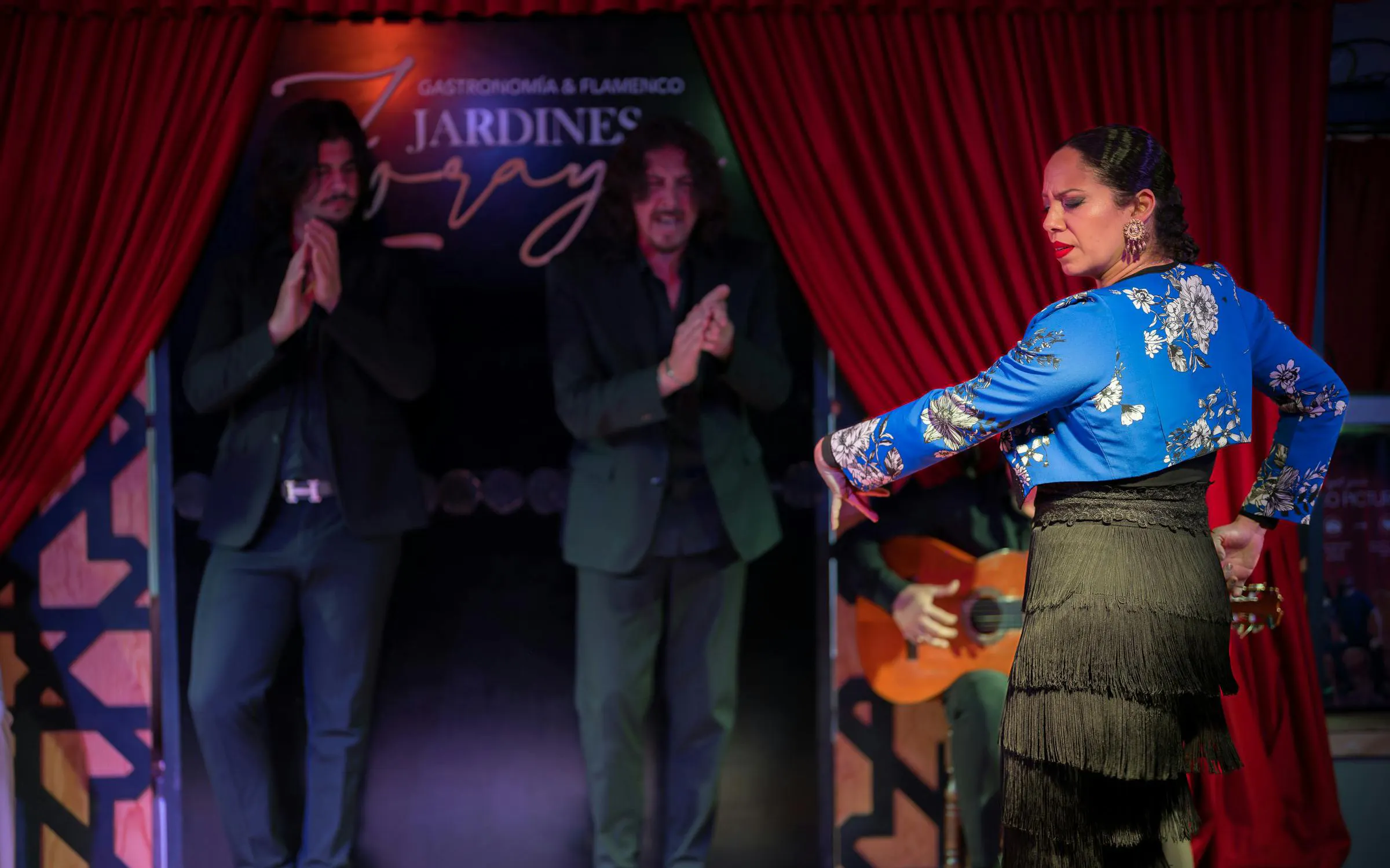 Flamenco dancer performing at Tablao Jardines de Zoraya with musicians in the background.