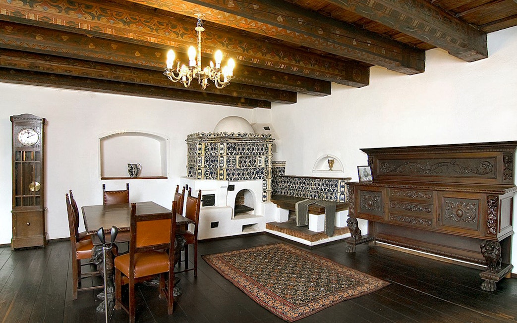 Bran Castle interior with ornate stove, wooden dining table, and antique furniture.