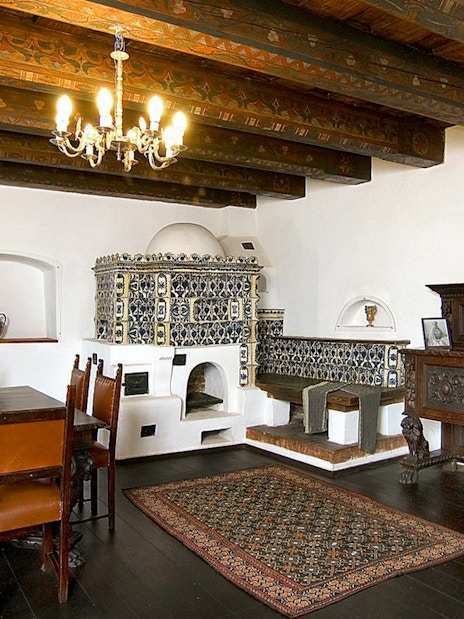 Bran Castle interior with ornate stove, wooden dining table, and antique furniture.