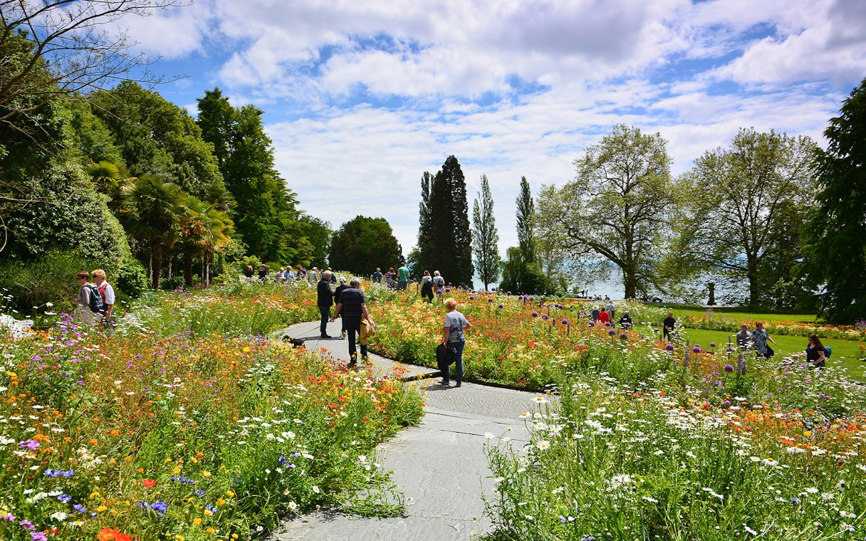 Visitors walking through colorful flower gardens on Mainau Island, Lake Constance, Germany.
