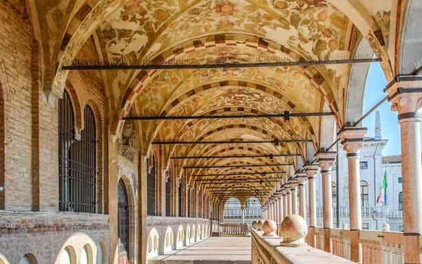 Arched walkway with frescoed ceiling in Padua, Italy, part of a guided walking tour.