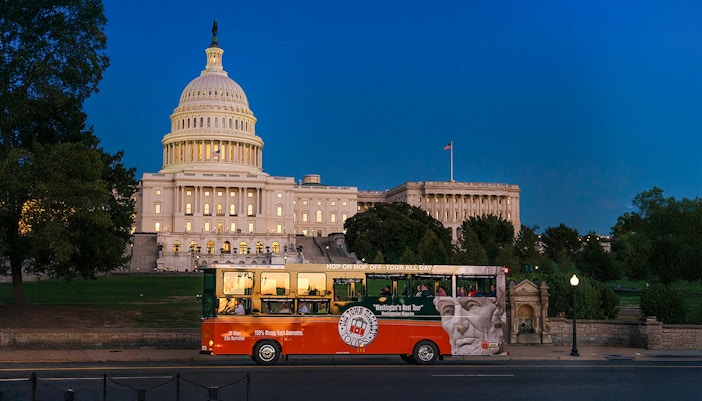 Tour bus passing by illuminated Capitol Hill at night, Washington, DC.
