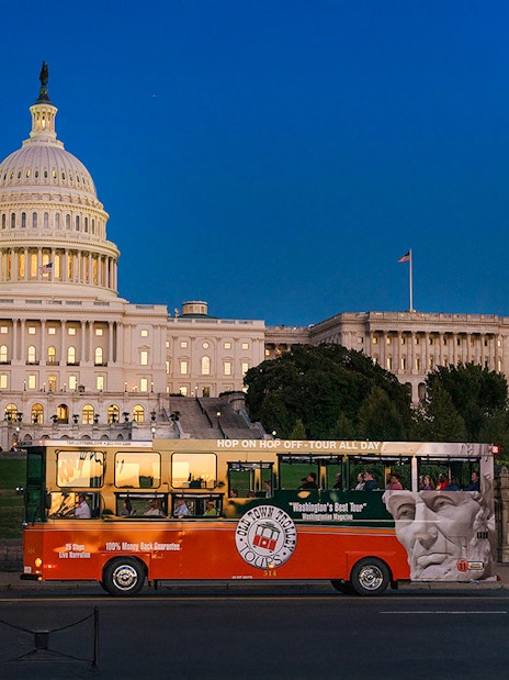 Tour bus passing by illuminated Capitol Hill at night, Washington, DC.