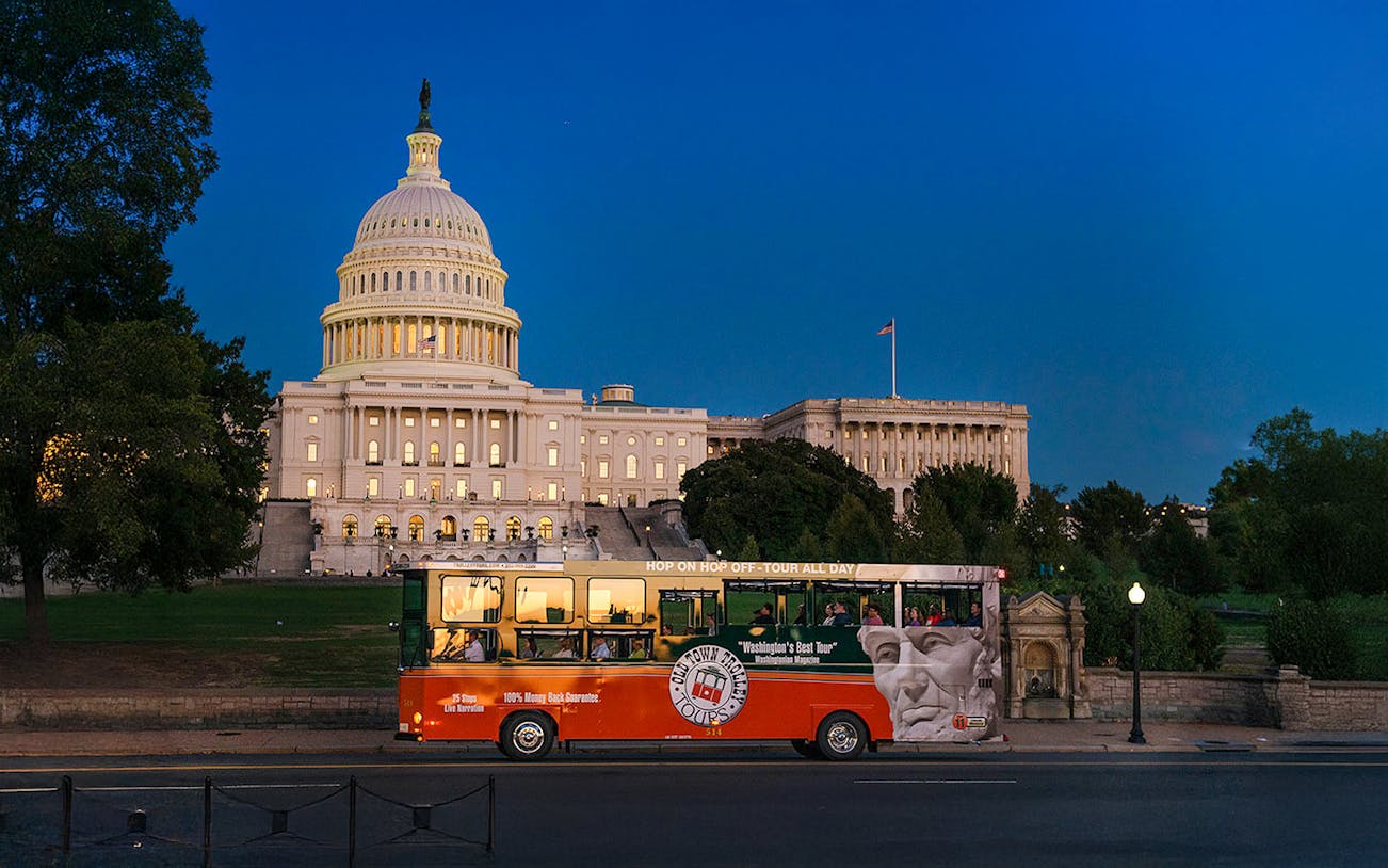 Tour bus passing by illuminated Capitol Hill at night, Washington, DC.