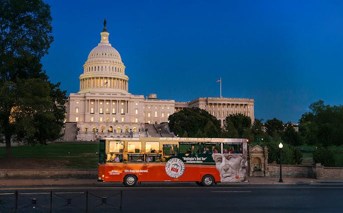 Tour bus passing by illuminated Capitol Hill at night, Washington, DC.