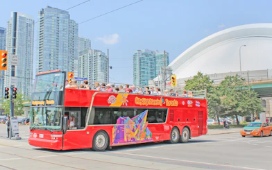 Tourists on a City Sightseeing bus exploring Toronto with CN Tower in the background.