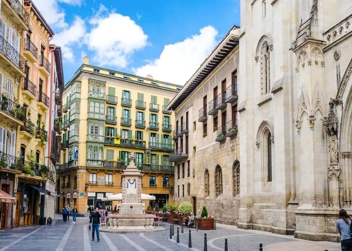 Street view in Bilbao with historic buildings and a central fountain, part of the Guggenheim and Gaztelugatxe tour.