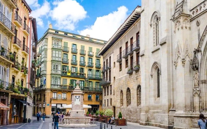 Street view in Bilbao with historic buildings and a central fountain, part of the Guggenheim and Gaztelugatxe tour.