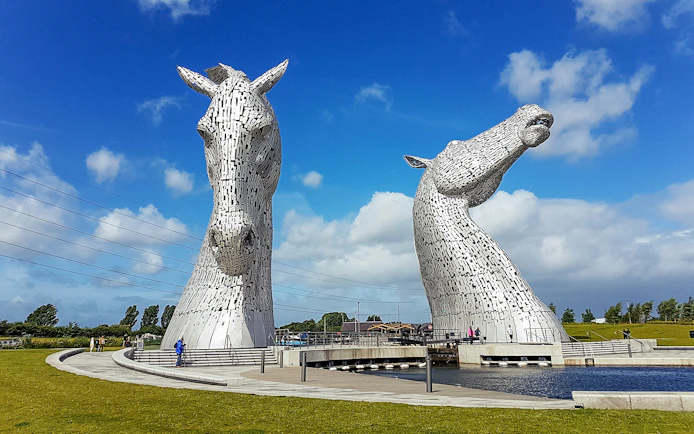Kelpies sculptures in Falkirk, Scotland, under a blue sky.