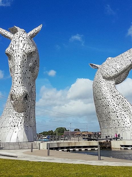 Kelpies sculptures in Falkirk, Scotland, under a blue sky.