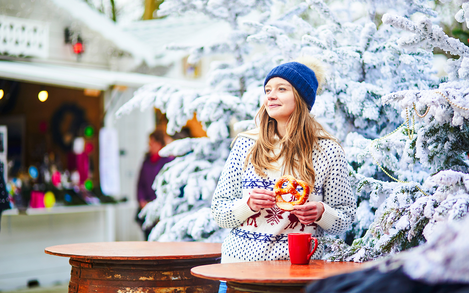 Person enjoying a pretzel at a winter market near the Eiffel Tower during New Year celebrations.