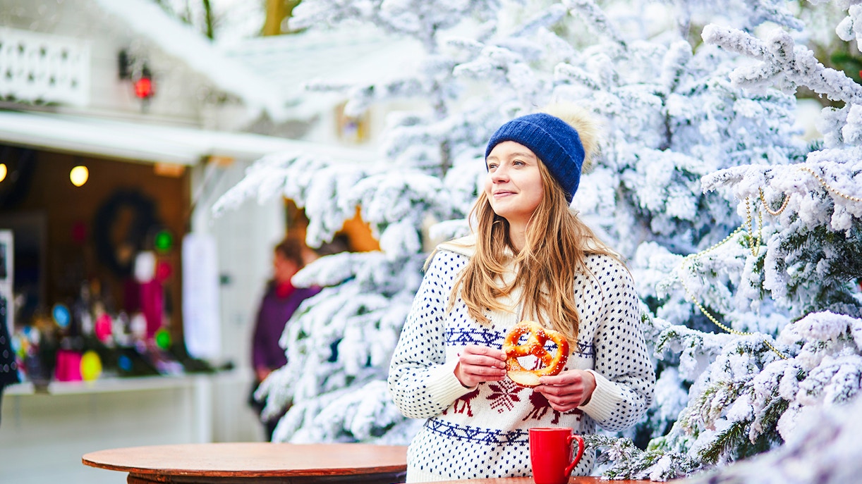 Person enjoying a pretzel at a winter market near the Eiffel Tower during New Year celebrations.