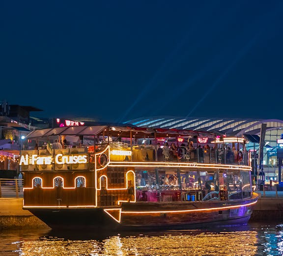 Dubai Canal evening cruise with illuminated boat and city lights.