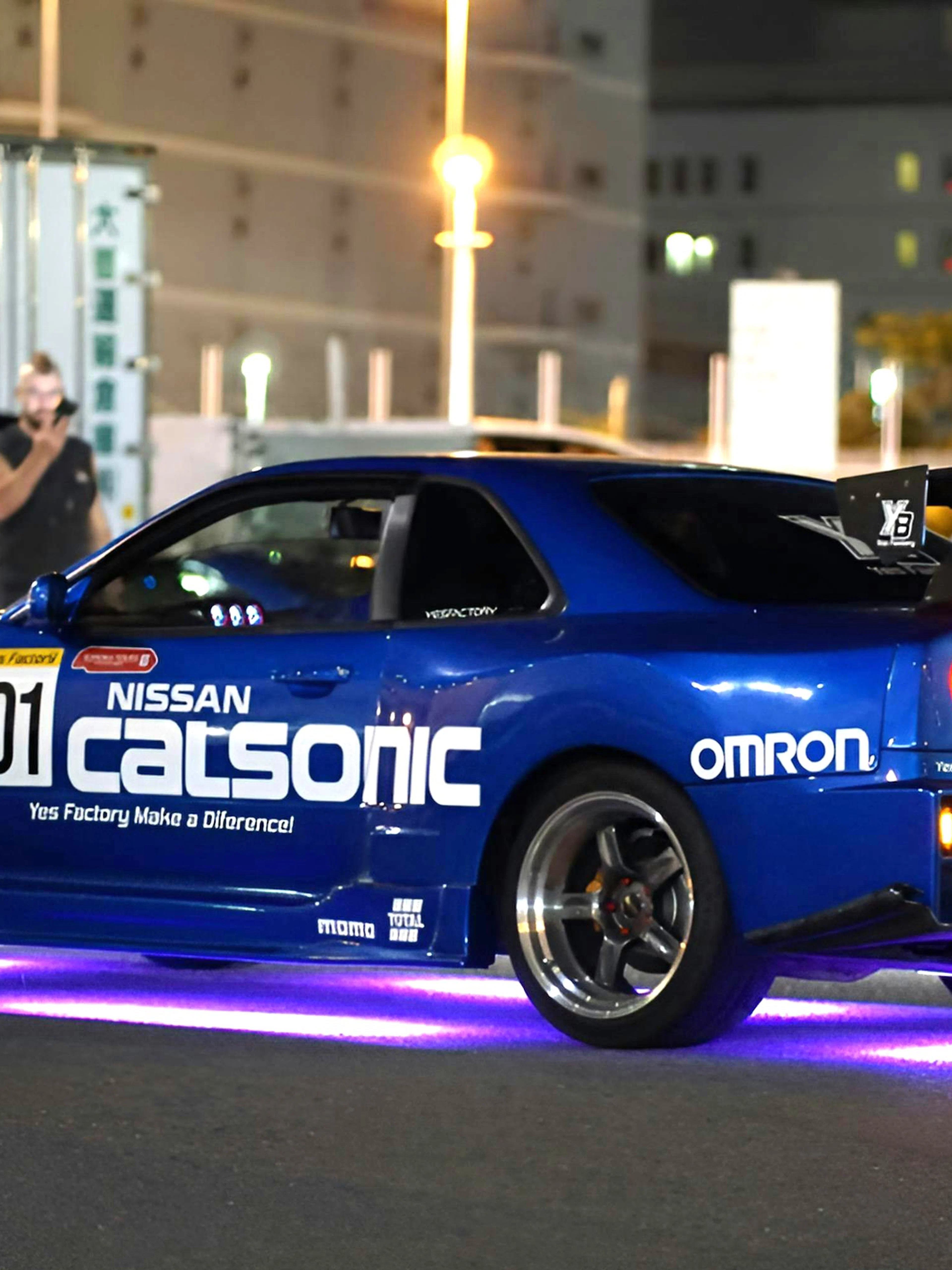 Nissan Skyline R34 at Daikoku PA car meeting, neon lights underneath.