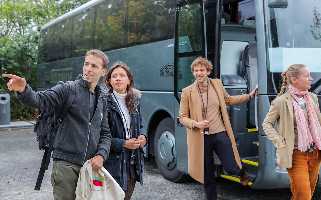 Visitors disembarking a bus on a guided tour from Paris to Mont Saint-Michel.