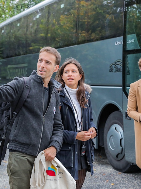 Visitors disembarking a bus on a guided tour from Paris to Mont Saint-Michel.