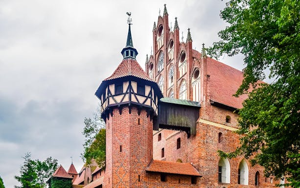 Malbork Castle's Gothic architecture with red brick towers, viewed on a tour from Gdańsk.