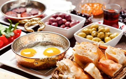 Turkish breakfast with fried eggs, olives, bread, and tea.