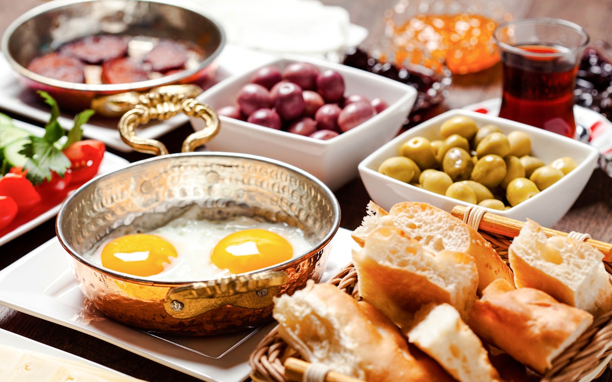 Turkish breakfast with fried eggs, olives, bread, and tea.
