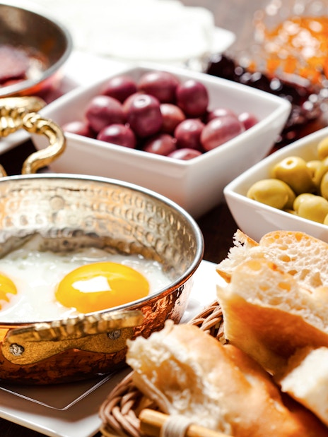 Turkish breakfast with fried eggs, olives, bread, and tea.